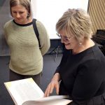 Diāna Zande kopā ar lekcijas klausītāju aplūko grāmatu.