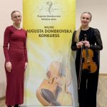 Daniela Jukša un Viktorija Tjuha pie Mazā A.Domrovska konkursa infostenda.